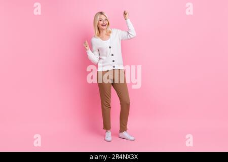 Full length portrait of overjoyed glad aged lady raise fists accomplishment isolated on pink color background Stock Photo