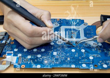 Motherboard repair. Motherboard, solder parts, male, close-up. Stock Photo