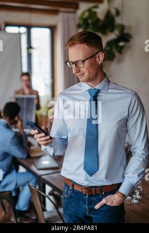 Portrait of confident young businessman using smart phone during meeting. Stock Photo