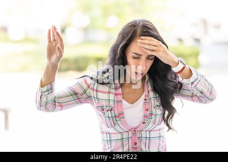 The young woman suddenly feels dizzy and struggles to keep her balance. Disoriented woman suffering from vertigo. Stock Photo