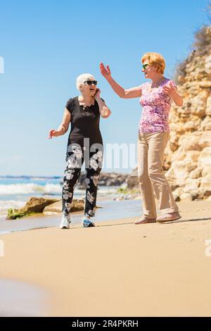 Two senior women walking along the rocky seashore Stock Photo