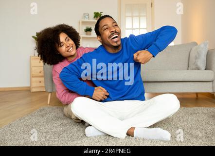 Cheerful Black Spouses Cuddling Playfully Holding Hands, Flirting Indoors Stock Photo