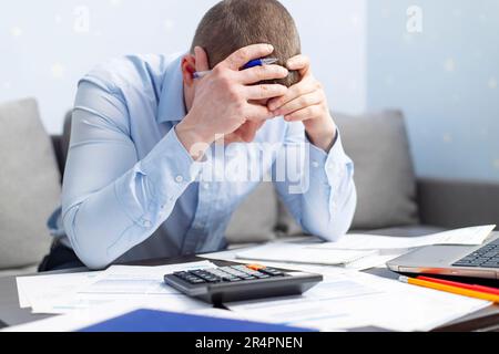 Distressed man sit at desk paying bills feel stressed having financial problems Stock Photo