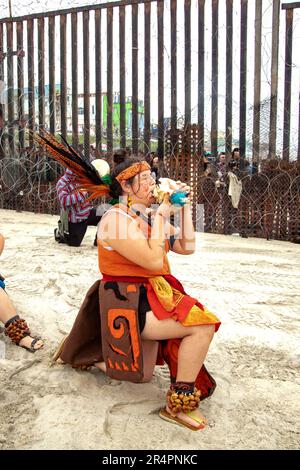 At Border Field Park near San Diego, multiracial demonstrators perform Native American dances at the US/Mexico border in support of Mexicans denied ac Stock Photo