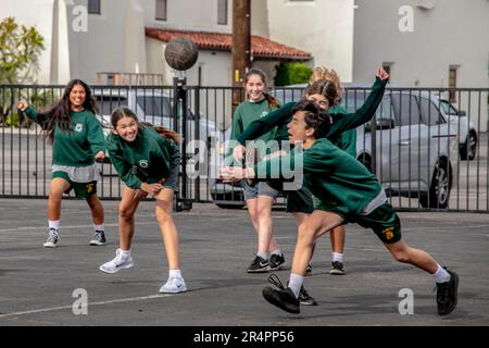 Uniformed multiracial students play lunchtime soccer at a Southern California Catholic middle school. Stock Photo