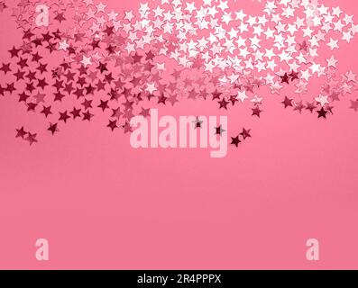 Metallic stars confetti on festive Viva Magenta color paper background with copy space. Trendy color 2023. Via Magenta color background. Stock Photo