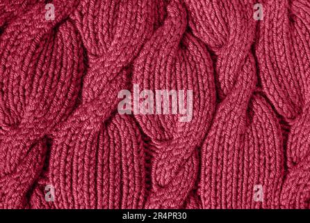 The texture of a warm knitted sweater. Beautiful handmade knitted repeating pattern. Demonstrating the colors of 2023 - Viva Magenta. Stock Photo