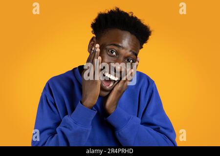 Emotional cheerful african american guy laughing on yellow Stock Photo