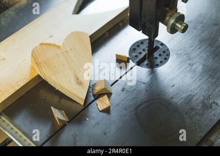 Heart shape cut from wooden plank placed next to wood milling machine in studio. High quality photo Stock Photo