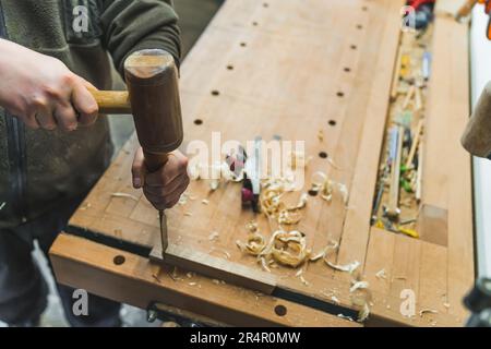 Hands of a carpenter using a chisel and hammer to carve wood on the workbench. High quality photo Stock Photo