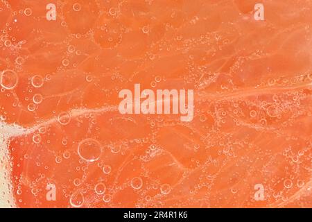 Close-up of a grapefruit slice in liquid with bubbles. Slice of ripe grapefruit in water. Close-up of fresh grapefruit slice covered by bubbles. Macro Stock Photo