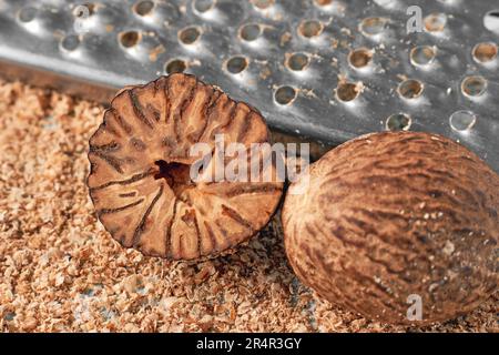 Two nutmegs on the background of a metal grater and grated nutmeg powder Stock Photo