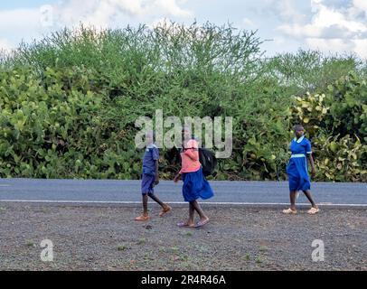 Three students in school uniform walking on the road. Kenya, Africa. Stock Photo