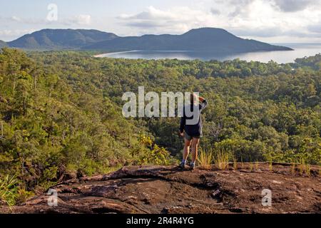 Woman looking over Zoe Bay from the top of Zoe Falls, Hinchinbrook Island Stock Photo