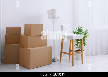 Boxes, lamp and chair wrapped in stretch film indoors Stock Photo