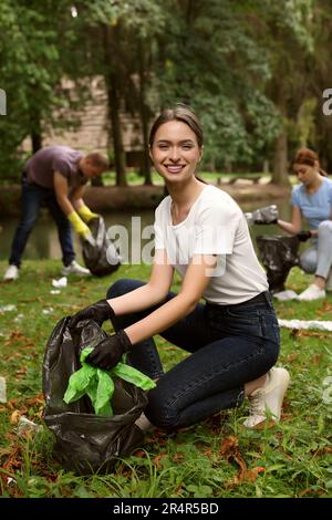 Woman with plastic bag collecting garbage in park Stock Photo