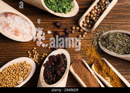 Scoops with different spices on wooden table, flat lay Stock Photo