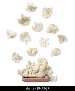 Many fresh cauliflower florets falling onto wooden plate on white background Stock Photo