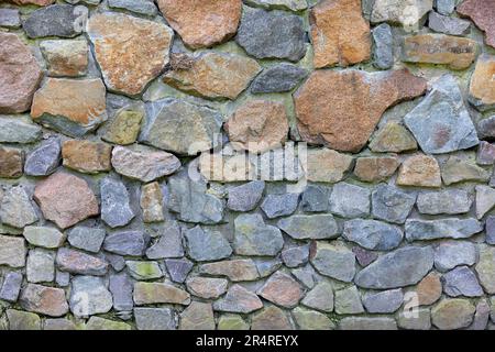 Stone wall paved with large cobblestones. A small bird sits on a twisted nest between stones. Natural texture and background. Stock Photo