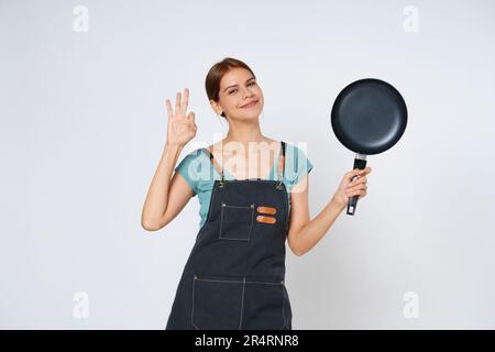 Restaurant owner sme woman showing OK sign and holding pan isolated on white background. Stock Photo