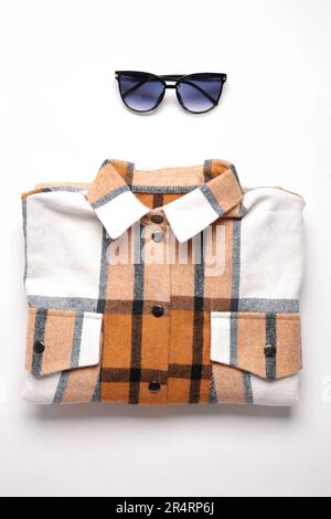 Multi-colored checkered women's shirt lying neatly folded on a light background. Top view Stock Photo