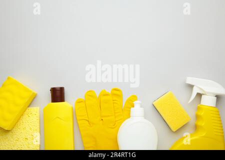 Cleaning Set. Yellow and white tools for cleaning. Cleaning agents, spray, rubber gloves on grey background. Flat Lay Stock Photo