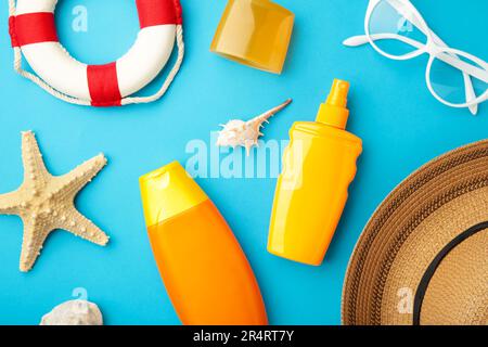 Sunscreen bottle with hat, glasses and other accessories on blue background. Cosmetics for safe sunburn. Sun protection cream Stock Photo