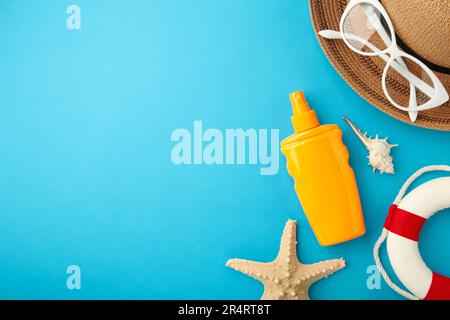 Sunscreen bottle with hat, glasses and other accessories on blue background. Cosmetics for safe sunburn. Sun protection cream Stock Photo