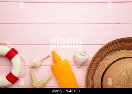 Sunscreen bottle with hat, glasses and other accessories on pink background. Cosmetics for safe sunburn. Sun protection cream with copy space Stock Photo