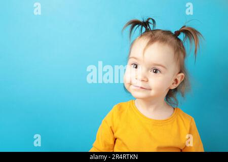 Little beautiful smiling girl poses faces on blue background. Portrait of baby  girl with copy space for text. Top view Stock Photo - Alamy