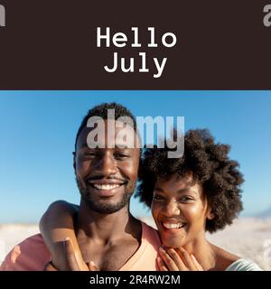 Composition of hello july text over african american couple on beach Stock Photo