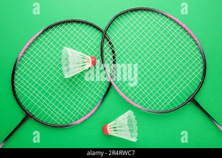 Shuttlecocks and badminton rackets on green background. Top view. Stock Photo