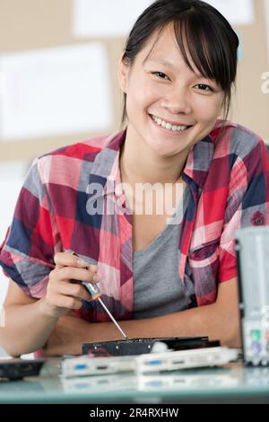young woman using screwdriver while working on computer component Stock Photo
