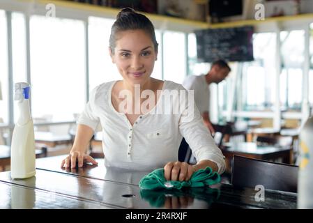 portrait of smiling waitress cleaning bar counter in bar Stock Photo