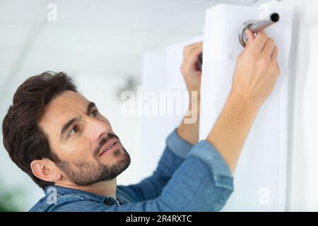 young man installing curtains over window Stock Photo