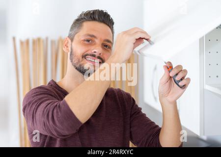 man installing kitchen cupboard Stock Photo