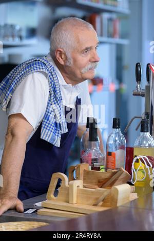 senior bartender serving customer at counter Stock Photo