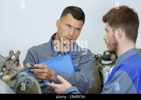 engineer teaching apprentices to use computerized metal processing machines Stock Photo