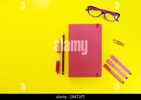 Red closed diary, notebook with pen, pencil, marker and glasses. Flat lay, back to school, learning, business, planning. Copy space Stock Photo