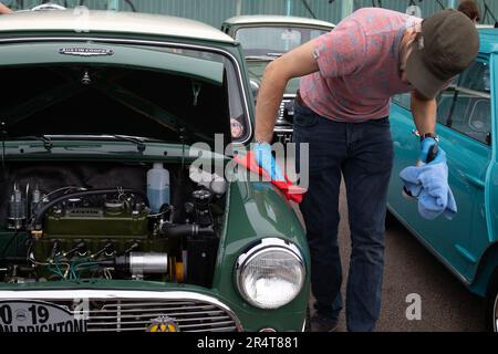 Brighton, UK - May 19 2019:  A green Mini car is on display with an open bonnet while its owner polishes it at the London Brighton Mini Run 2019 Stock Photo