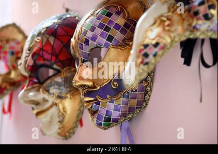 Profile view of traditional Venetian masks for carnival hanging in row on pink wall in Venice, Italy. Stock Photo