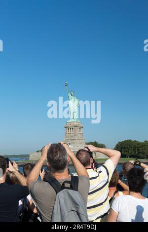 US, New York, Tourists taking pictures of the Statue of Liberty from the Hudson river ferry boat. Stock Photo