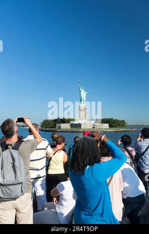 US, New York, Tourists taking pictures of the Statue of Liberty from the Hudson river ferry boat. Stock Photo