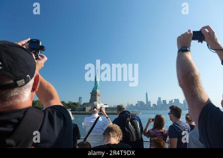 US, New York, Tourists taking pictures of the Statue of Liberty from the Hudson river ferry boat. Stock Photo