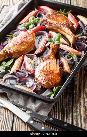 Baked pork chops with caramelized onions and rhubarb close-up in a baking sheet on the table. Vertical Stock Photo