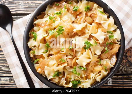 Austrian noodles with stewed white cabbage and caramelized onions close-up in a bowl on the table. Horizontal top view from above Stock Photo