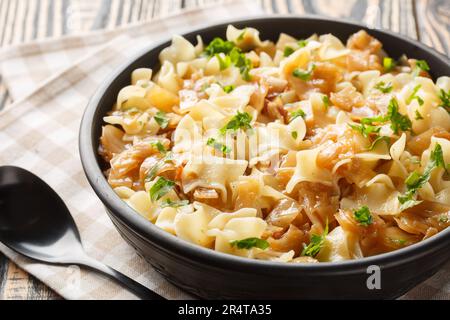 Austrian noodles with stewed white cabbage and caramelized onions close-up in a bowl on the table. Horizontal Stock Photo