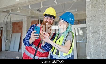 Man and woman builders using smartphone working at construction site Stock Photo