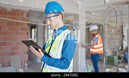 Two men builders writing document working at construction site Stock Photo