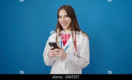 Young hispanic woman doctor smiling using smartphone over isolated blue background Stock Photo